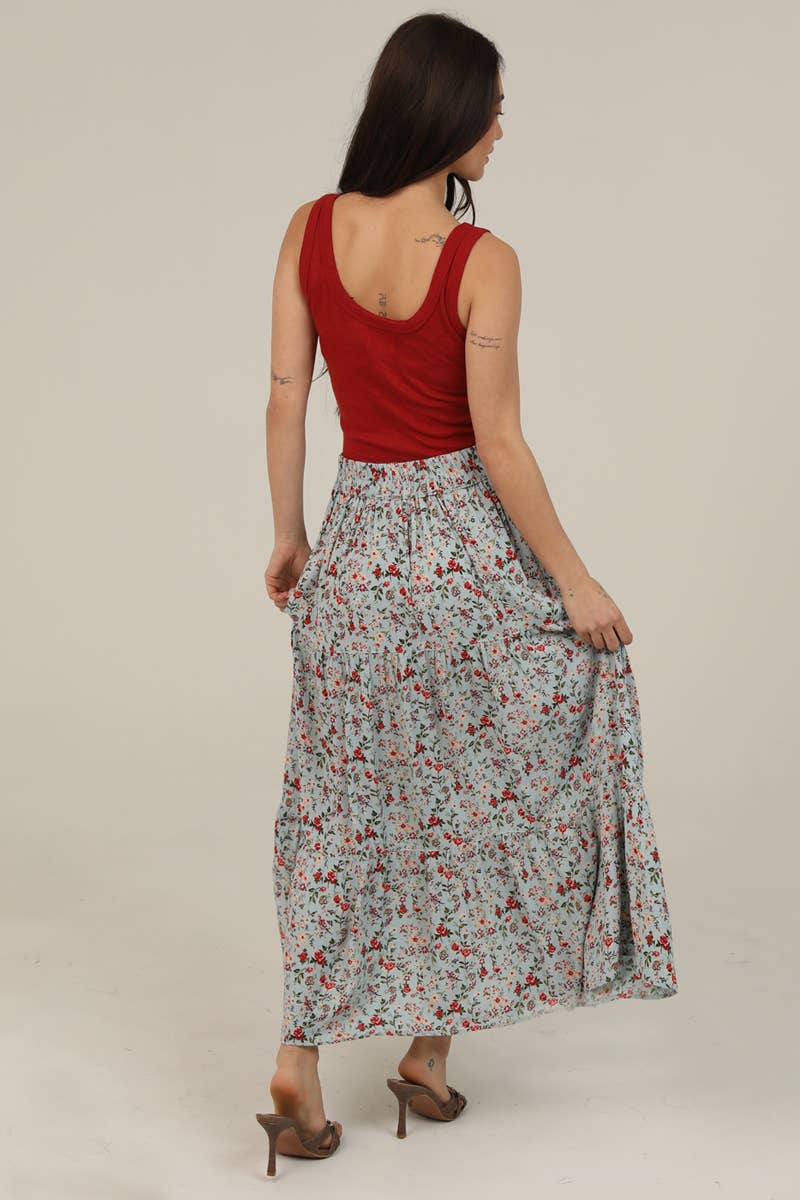 Woman wearing a red top and floral skirt on a plain background