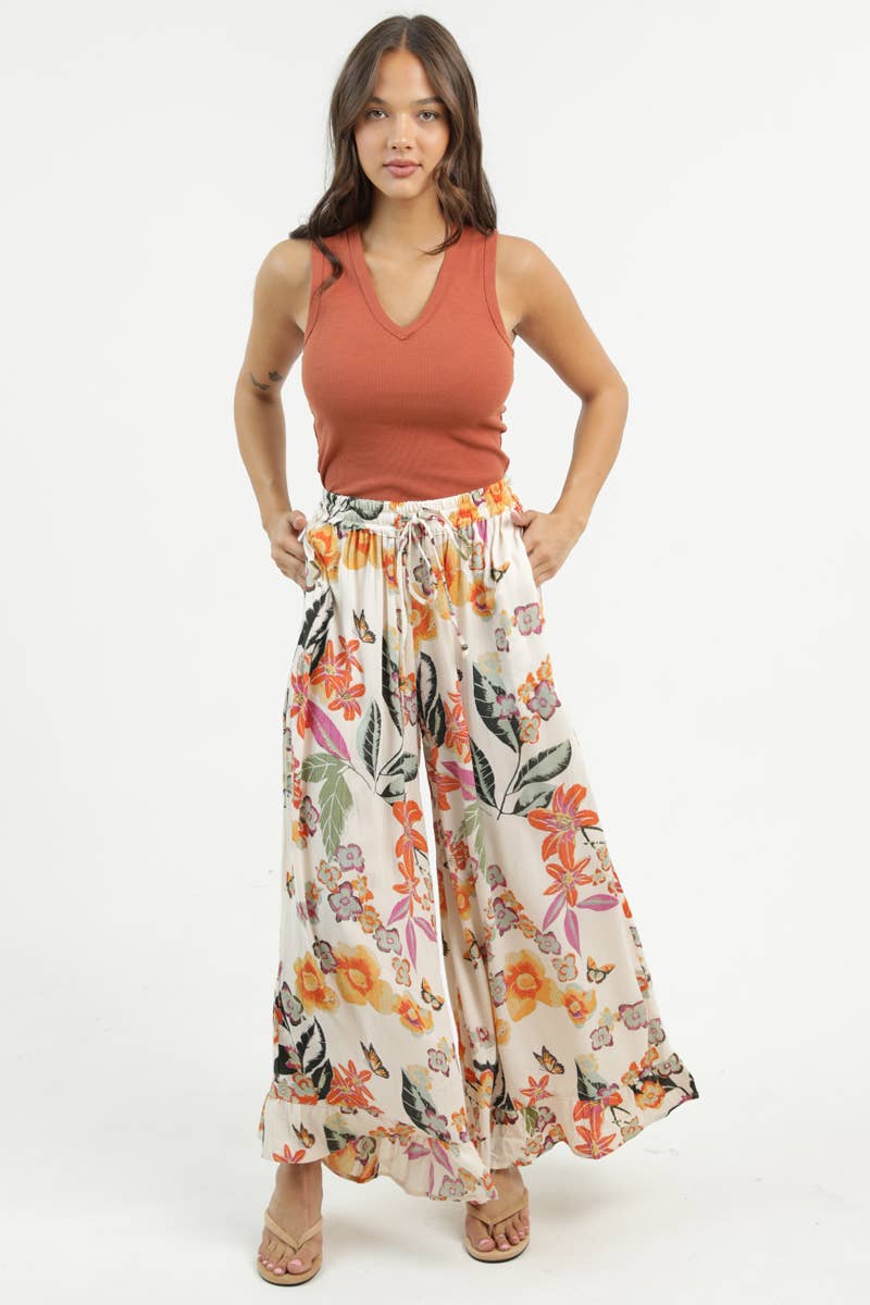 Woman facing foward wearing a rust-colored sleeveless top and Angie floral wide-leg pants on a white background