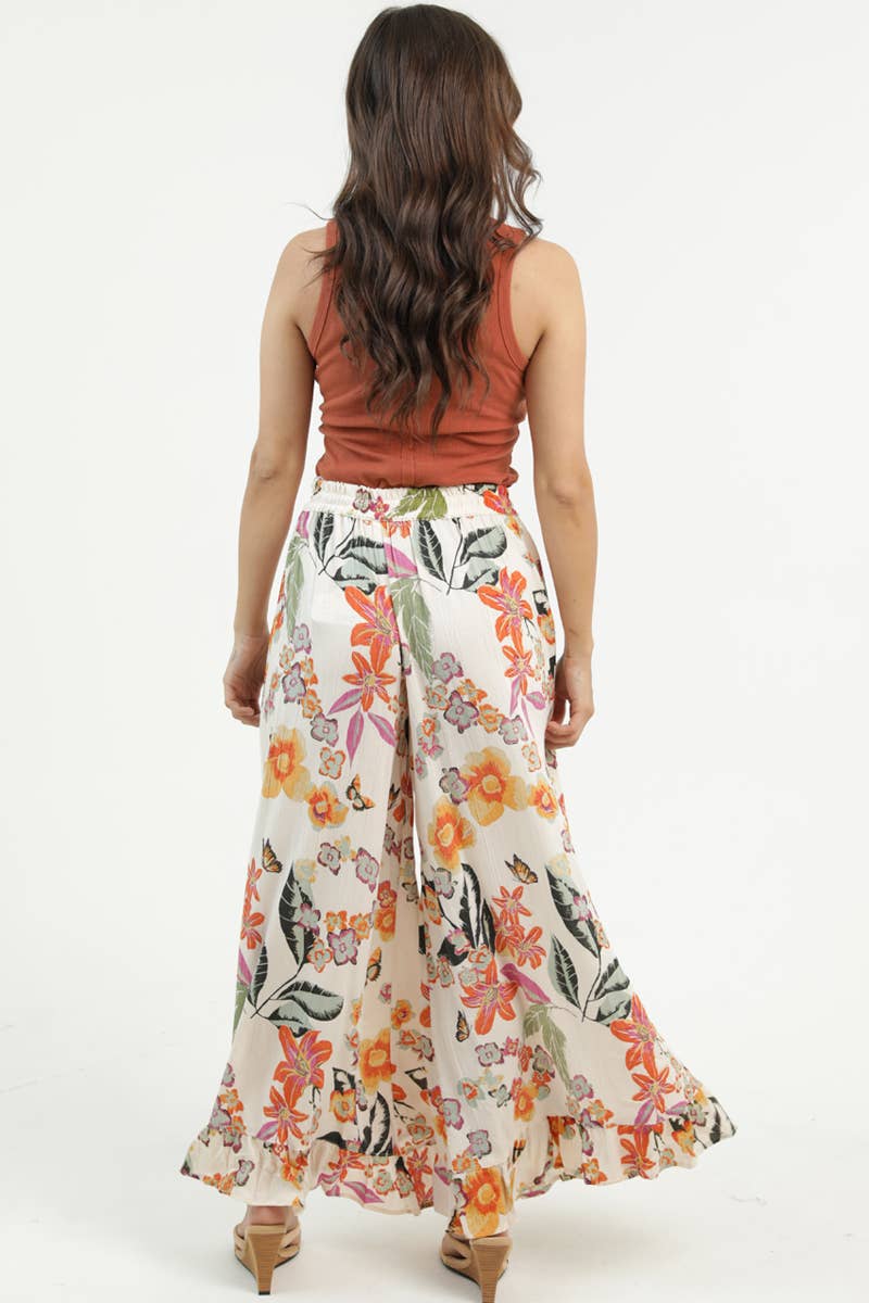 Woman facing backwards wearing a rust-colored sleeveless top and Angie floral wide-leg pants on a white background