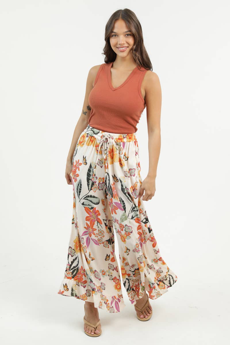 Woman facing foward wearing a rust-colored sleeveless top and Angie floral wide-leg pants on a white background